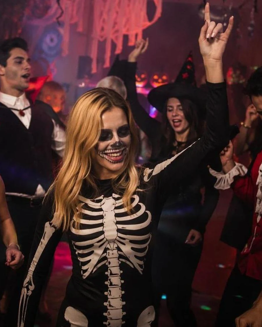 Halloween party crowd dancing in skeleton and vampire costumes