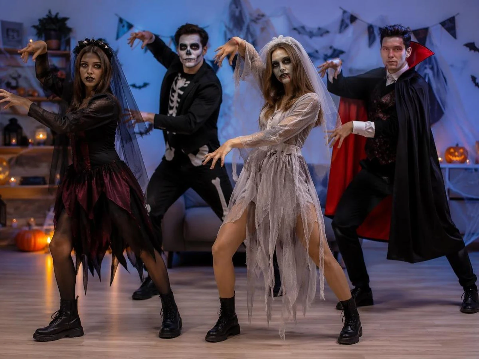 Four dancers in Halloween costumes performing in a candlelit castle hall