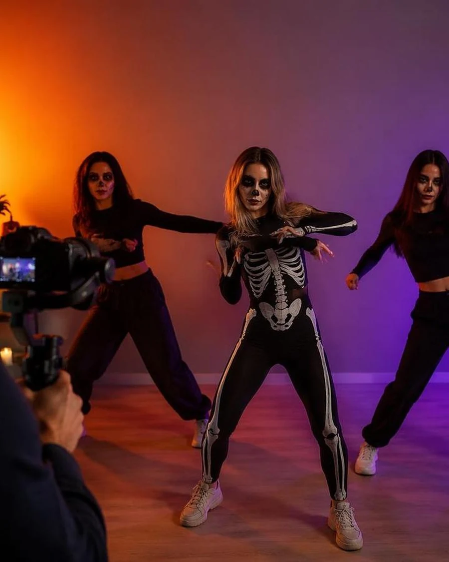 Three dancers in black costumes performing a skeleton routine under purple lights